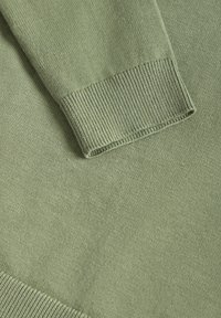 Pull vert clair en tricot montrant un tissu texturé avec des poignets côtelés et une finition lisse.