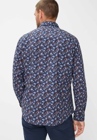 Langermig shirt met een blauw bloemenpatroon op een donkere achtergrond, met een kraagnekkraag en knoopmanchetten. Het materiaal lijkt licht van gewicht.