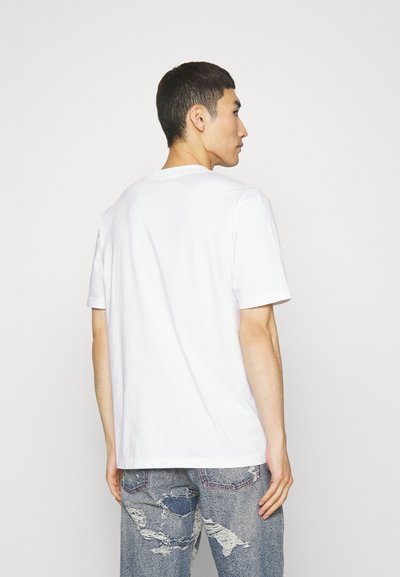 Weißes Baumwoll-T-Shirt mit kurzen Ärmeln, Rundhalsausschnitt, geradem Saum und minimalistischem Design. Trage dazu ausgewaschene Diesel-Jeans.