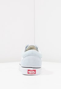 Sneaker in suede blu chiaro e tessuto bianco con suola in gomma piatta, bordi neri e logo rosso "Vans Off The Wall" sul tallone.