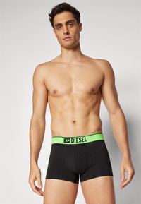 Μαύρα μποξεράκια με φωτεινό πράσινο λάστιχο στη μέση, που φέρουν το λογότυπο "DIESEL", σε εφαρμοστή σχεδίαση και απαλή υφή.