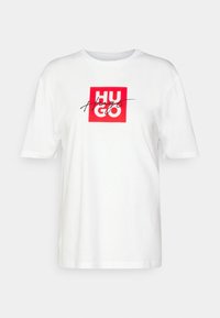 Biely bavlnený tričko s červeným štvorcovým grafickým motívom s textom "HUGO" a kurzívou "Hugs" na prednej strane. Krátke rukávy a okrúhly výstrih.