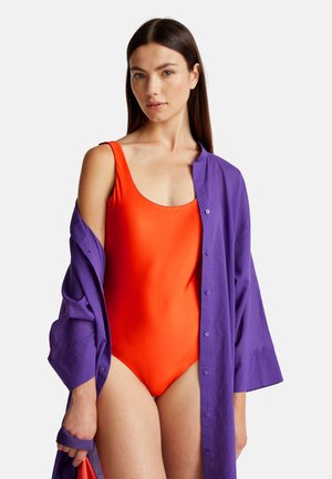 Felroze zwempak met een ronde hals, gecombineerd met een losse, lange mouwen, knoopshirt van paarse stof.