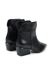 Czarne skórzane botki za kostkę z szpiczastym noskiem, niskim obcasem w kształcie bloku i gładką teksturą. Szwy biegną wzdłuż boków.