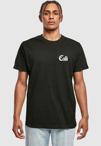 Zwart katoenen t-shirt met een witte "Cali" afbeelding op de linkerkant van de borst. Klassiek crew neck ontwerp met korte mouwen en een normale pasvorm.