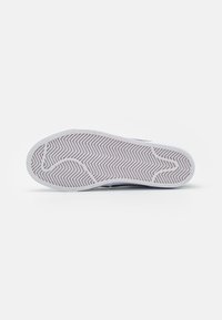 Rubber sneaker sole in white, featuring a herringbone pattern for grip. The edges are slightly rounded, with a smooth texture.
