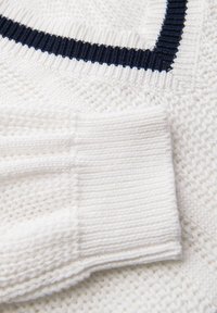 Maglione bianco lavorato a maglia con un motivo testurizzato, maniche a costine e un accento blu navy lungo il collo. Tessuto morbido con una sensazione accogliente.