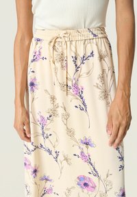 Ljusbeige blommig kjol med lila och rosa blommönster, elastisk midja med dragsko, mjuk tygtextur.