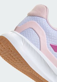 Zapatilla deportiva de color púrpura claro con una parte superior de malla texturizada, detalles en rosa y una entresuela blanca. La suela de goma presenta un diseño de dibujo en el patrón de la banda de rodadura.