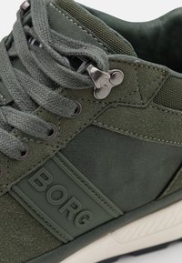 Groene sneaker gemaakt van suede en synthetische materialen, met veters, metalen oogjes, een rubberen zool en een opvallend "BORG" logo detail.