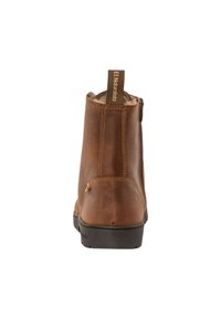 Bota de cuero marrón hasta el tobillo con cierre lateral, punta redondeada, costuras en tono beige y una tira en la parte trasera. Suela de goma negra.