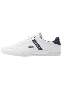 Baskets Lacoste blanches en cuir texturé, avec des accents navy, une rayure rouge et navy, et un logo de crocodile vert sur le côté.