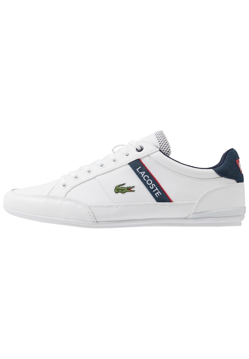 Baskets Lacoste blanches en cuir texturé, avec des accents navy, une rayure rouge et navy, et un logo de crocodile vert sur le côté.