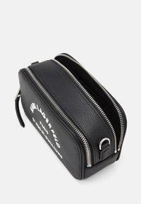 Czarna torba ze strukturalnej skóry z podwójnymi srebrnymi suwakami, z białym nadrukowanym tekstem po jednej stronie oraz boczną pętlą do mocowania.