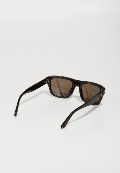Ochelari de soare tortoise brown cu rame rectangulare și lentile tonificate în nuanțe de brown. Prezintă curbe moi și detalii cu balama pe temple.