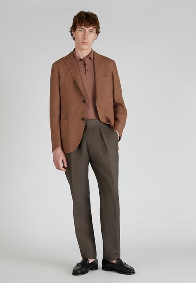 Bruine, gestructureerde blazer over een aansluitende, bruine polo; gecombineerd met donkergrijze, geplooide broeken en zwarte instappers, minimalistisch ontwerp.