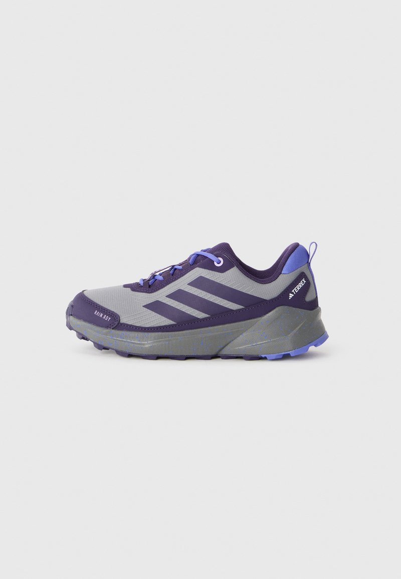 Sapatilha de corrida em trilha Adidas Terrex em roxo e cinza, com fecho de atar e sola texturizada, contra um fundo branco.