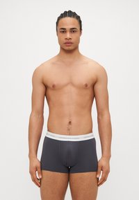 Boxer-briefs en coton gris avec une taille blanche portant "Copenhagen Studios" en texte gris, design ajusté et texture douce.