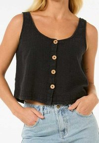 Schwarzes, bauchfreies Tanktop mit rundem Ausschnitt, versehen mit Holzknöpfen vorne und einem strukturierten Stoff. Kombiniert mit hellblauen Jeans.