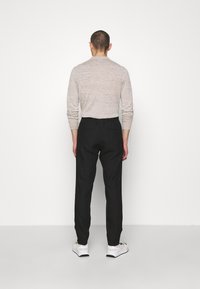 Světle šedá košile s dlouhým rukávem v kombinaci s černými kalhotami a bílými teniskami. Zadní pohled ukazuje jednoduchý design a pohodlný střih obou kousků.