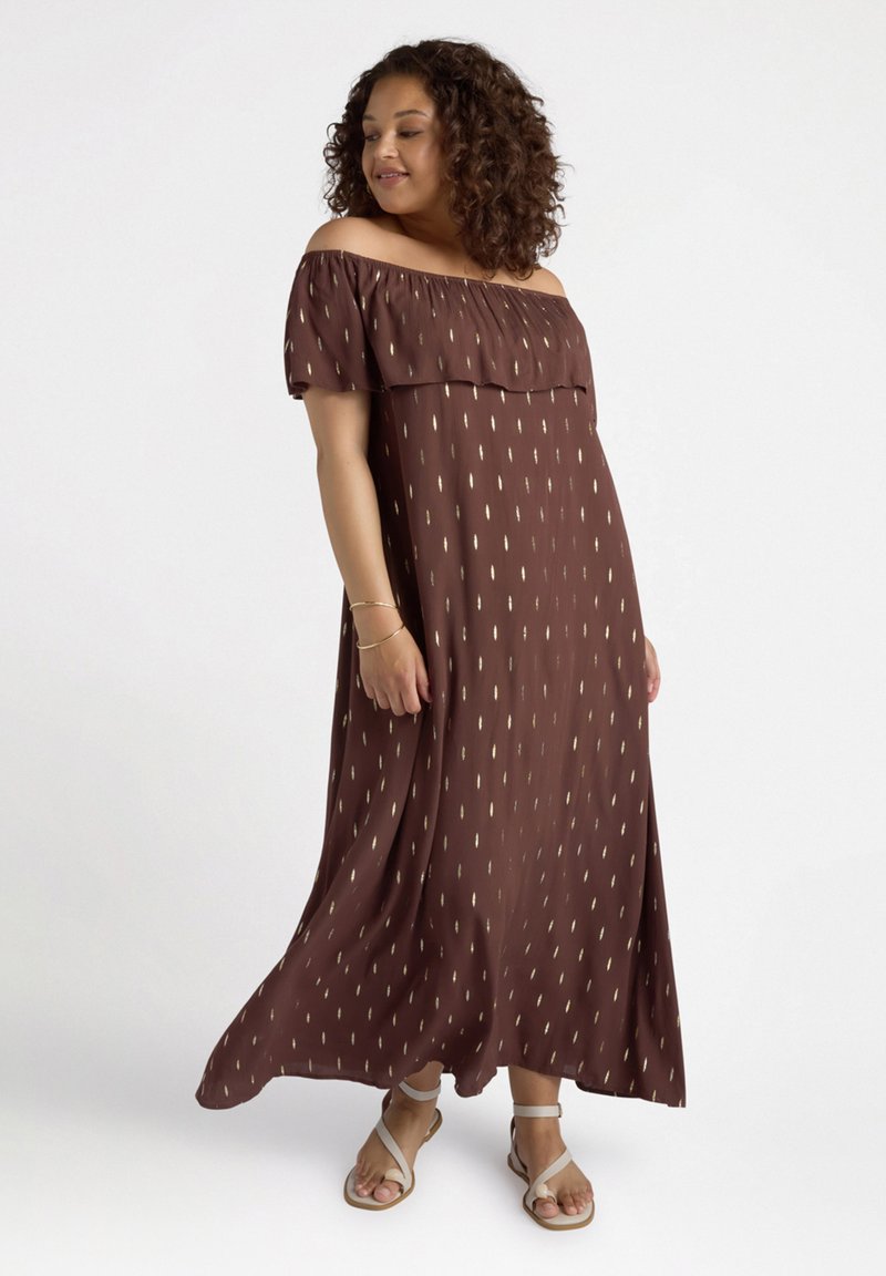Brun off-the-shoulder maxikjole med gyldne diagonale mønstre, let flydende stof og en afslappet pasform. Bæres med beige sandaler.