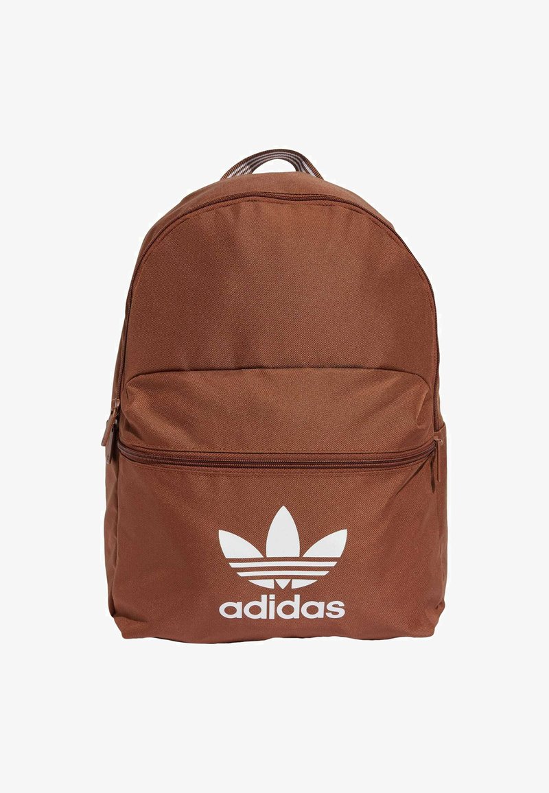 Ruskea kangaskoukku, jossa on pyöreä muoto, etupuolella vetoketjutasku ja valkoinen Adidas-logo, jossa on kolme lehtikoristetta.
