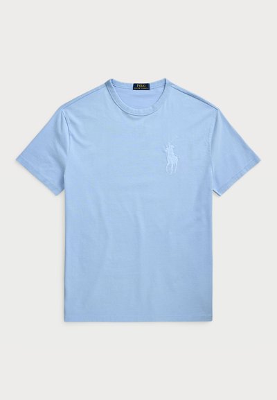 Světle modré bavlněné tričko s krátkým rukávem a kulatým výstřihem. Obsahuje vyšívané logo na levé části hrudníku. Hladká textura.