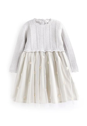 Haut en tricot gris clair à manches longues attaché à une jupe beige avec un voile transparent et une petite broderie florale blanche.