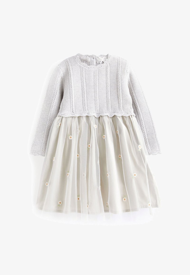Haut en tricot gris clair à manches longues attaché à une jupe beige avec un voile transparent et une petite broderie florale blanche.