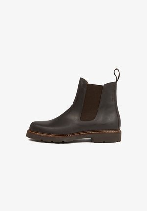 Bottines en cuir marron avec panneaux élastiques sur les côtés, bout arrondi et semelle en caoutchouc texturé. Caractérisées par un liseré cousu et une anse au talon.