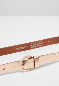 Rose gold textured leather belt with a round metallic buckle, featuring a brown underside labeled "Vanzetti Real Leather Made in Germany."