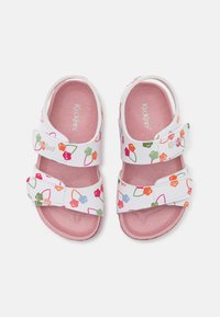 Sandalias blancas con patrones florales en rosa, verde y naranja; con dos correas ajustables de Velcro y una plantilla suave en rosa.