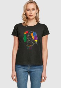Sort T-shirt med farverig linjekunst af tre profilansigtet med teksten "KÆRLIGHED ER KÆRLIGHED" i en gradient nedenfor. Korte ærmer, afslappet pasform.