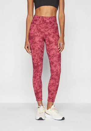 Leggings de cintura alta en rojo intenso con ligeros patrones florales. Confeccionados con tela elástica. Combinados con zapatillas ligeras.