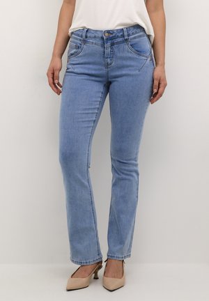 Jeans in denim azzurro chiaro con un design a gamba dritta, dotati di tasche anteriori e chiusura con bottone. Abbinati a scarpe col tacco alte di colore beige.