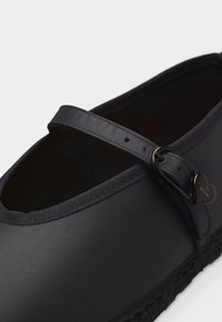 Μαύρο παπούτσι στυλ Mary Jane με λουράκι και μεταλλική καρδιά ως αγκράφα με την επιγραφή "Love Moschino".