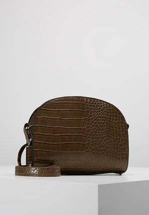 Brown crocodile-texture leather crossbody bag with rounded top and adjustable strap on white pedestal against gray background.