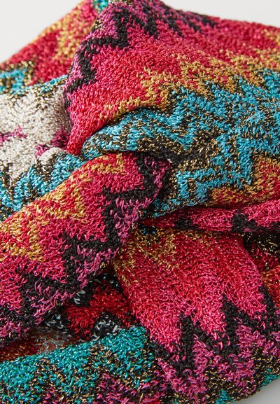 Țesătură tricotată colorată în roz, negru, aur și turcoaz, cu un model în zigzag; textură moale cu un luciu metalic.