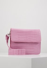 Borsa in sintetico rosa con una finitura lucida a motivo coccodrillo, dotata di chiusura a pattina e tracolla removibile, esposta su una superficie bianca.