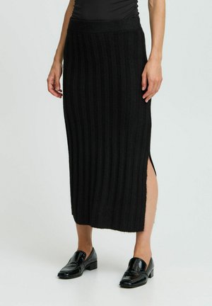 Jupe noire en tricot côtelé avec une fente sur le côté, taille ajustée et design mi-long. Texture lisse, style minimaliste.