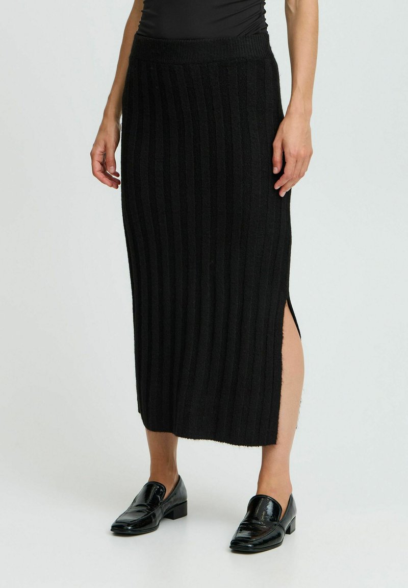 Jupe noire en tricot côtelé avec une fente sur le côté, taille ajustée et design mi-long. Texture lisse, style minimaliste.
