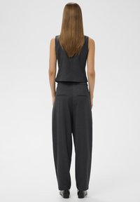 Tmavě šedý bezrukávový top v kombinaci s vysoko pasovými širokými kalhotami; látka má hladkou strukturu; minimalistický design s zadními kapsami.
