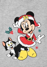 Minnie Mouse in un vestito rosso da Babbo Natale posa sorridendo con un gatto bianco e nero, bacche di agrifoglio e stelle rosse e verdi su sfondo grigio.