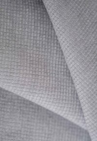 Textured gray fabric with a woven pattern, featuring a subtle sheen and a soft feel, arranged in overlapping folds.