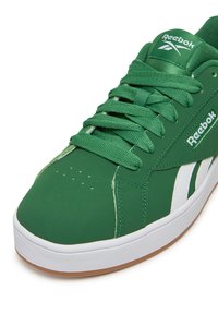 Zielone sneakersy z gładką syntetyczną cholewką, białą gumową podeszwą, fakturowanymi sznurówkami oraz logo Reebok po bokach i na języku.
