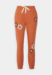 Sweatpants de cor ferrugem feitos de um tecido suave, com padrões florais brancos e pretos nas pernas. Inclui uma cintura elástica e cordão.