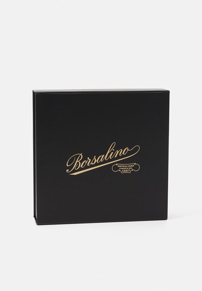 Melns taisnstūra rūtiņš ar zelta logotipu "Borsalino" un tekstu zem tā, izgatavots no gludas materiāla ar spīdīgu apdari.