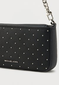 Μαύρο clutch από δέρμα με υφή βότσαλου, διακοσμημένο με ασημένιες μεταλλικές καρφίτσ ες σε σχήμα πλέγματος και μεταλλική αλυσίδα ως λουράκι. Το λογότυπο είναι ανάγλυφο σε ασημί στο μπροστινό μέρος.