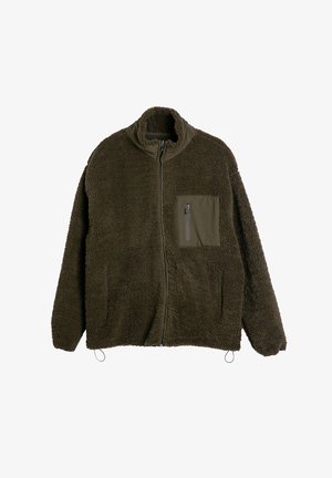 Vihreä froteetakki korkealla kauluksella, vetskari edessä ja rintatasku. Varustettu elastisella kiristysnauhalla helmassa ja tekstuurilla, joka tarjoaa lämpöä.