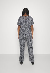 Námořnický overal s bílým swirl vzorem, krátké rukávy, volný střih a klíčová díra na zádech. Tkanina vypadá lehká a hladká.